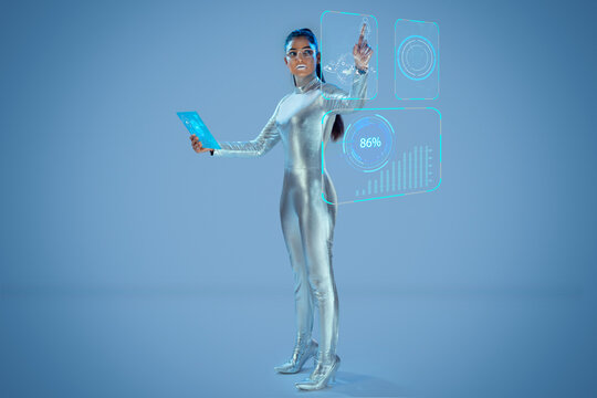 A model dressed as a robot wearing silver, futuristic  clothes holding a virtual  tablet, with virtual icons . A future technology concept