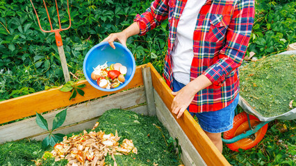 Kitchen waste, lawn clippings as composting ingredients close up. A woman throws food waste into a...