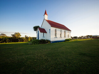 Old historic 19th century white presbyterian Awhitu Central Church with green grass, Manukau Heads...