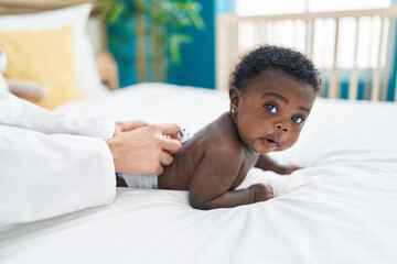 African american baby having medical examination lying on bed at bedroom