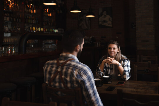 Confident owner of cafe interviewing young specialist. Manager of cafeteria or coffee shop job interview with young male bartender barista or waiter applied for work in the restaurant. Employee hiring