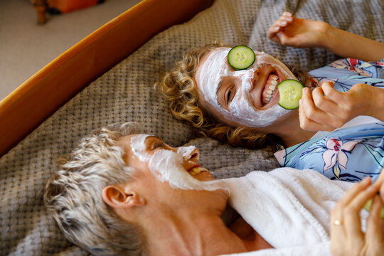 Mother and daughter spending quality time together wearing facial mask and cucumber.