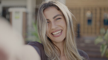 Young blonde woman smiling confident making selfie by camera at street