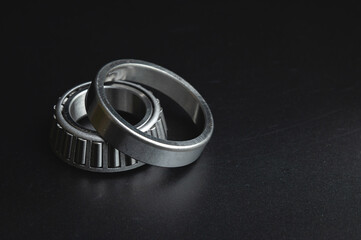 new two-piece roller bearing on a black background. Metal spare part for car suspension