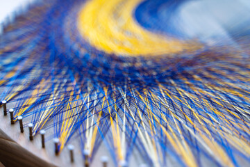 Colored thread mandala on a wooden board with nails. Mandala Moon Harmony Sun esotericism and...