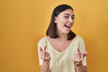 Hispanic girl wearing casual t shirt over yellow background showing middle finger doing fuck you...