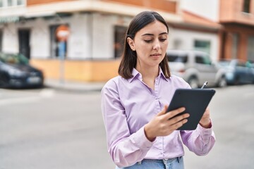 Young hispanic woman using touchpad at street