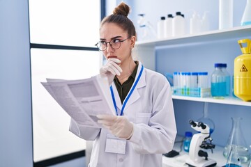 Young woman scientist reading document at laboratory