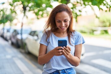 Young woman smiling confident using smartphone at street