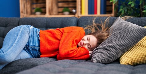 Obraz premium Young blonde woman lying on sofa sleeping at home