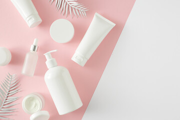 Summer skincare concept. Top view photo of cosmetic tubes, dropper bottle, pump bottle and tropical leaves on pastel pink and white background with empty space. Flat lay cosmetics mockup idea.