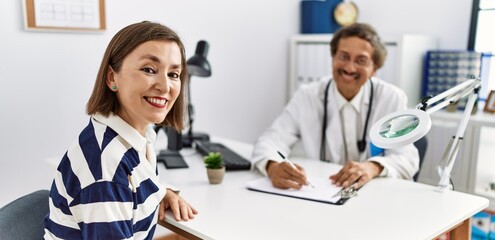 Obraz premium Middle age man and woman wearing doctor uniform having medical consultation at clinic