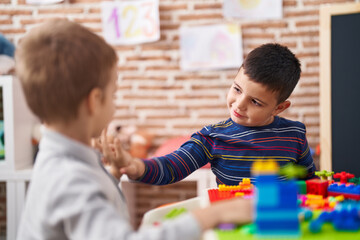 Two kids playing with construction blocks sitting on table at kindergarten