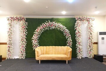 flower decoration on green grass wall with sofa in Banquet hall