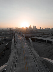 A cityscape view of the 6th street bridge and the downtown district skyline in Los Angeles during the sunset