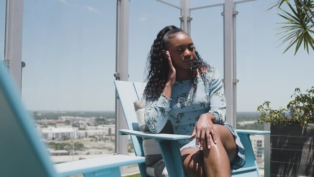 Black Stock Footage of happy, healthy, and successful Black woman wearing a sun dress on a luxury condominium rooftop on a sunny blue sky day