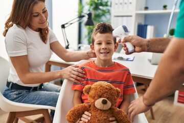 Family having medical consultation measuring temperature using thermometer at clinic