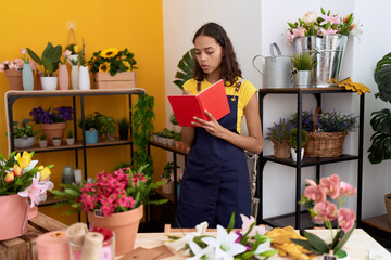 Young african american woman florist writing on notebook standing at flower shop