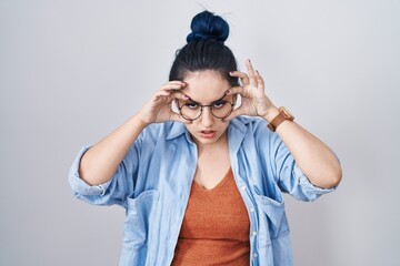 Young modern girl with blue hair standing over white background trying to open eyes with fingers, sleepy and tired for morning fatigue