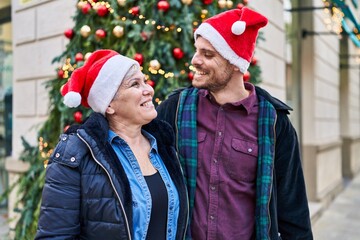 Mother and son hugging each other standing by christmas tree at street