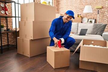 Young hispanic man worker packing package at new home