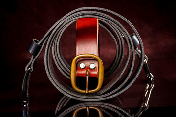 Leather belts with a buckle on a dark background.