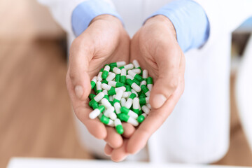 Young hispanic man pharmacist holding pills at pharmacy