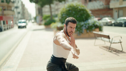 Young hispanic man karate fighter training at park