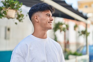 Young hispanic man smiling confident looking to the side at street