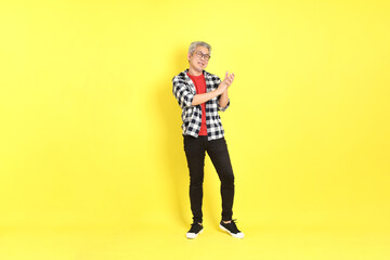 The 40s adult Asian man with casual dressed standing on the yellow background.