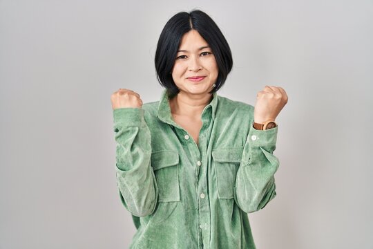 Young asian woman standing over white background celebrating surprised and amazed for success with arms raised and eyes closed. winner concept.
