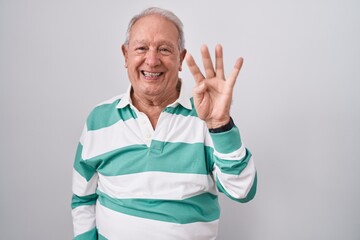 Senior man with grey hair standing over white background showing and pointing up with fingers...