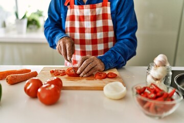 Senior man cutting tomato at kitchen