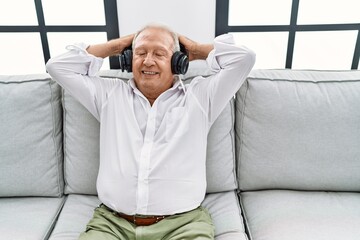 Senior man listening to music sitting on sofa at home