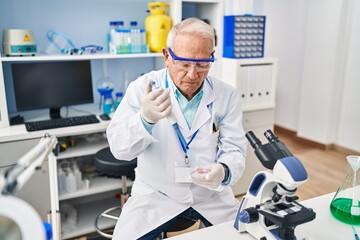 Senior man wearing scientist uniform using pipette working at laboratory