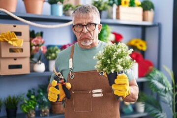 Hispanic man with grey hair working at florist shop depressed and worry for distress, crying angry and afraid. sad expression.