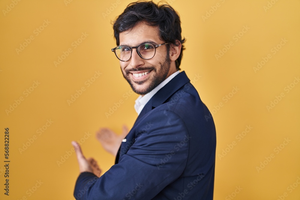 Sticker Handsome latin man standing over yellow background inviting to enter smiling natural with open hand