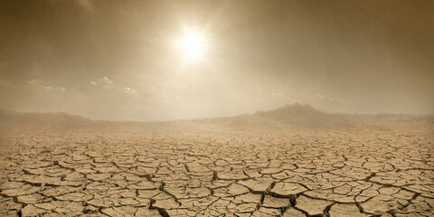 Barren terrain panorama, sun shining over cracked dried land and clouds of dust. Climate change...