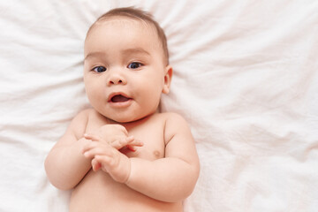 Adorable hispanic toddler smiling confident lying on bed at bedroom