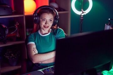 Redhead woman playing video games happy face smiling with crossed arms looking at the camera. positive person.