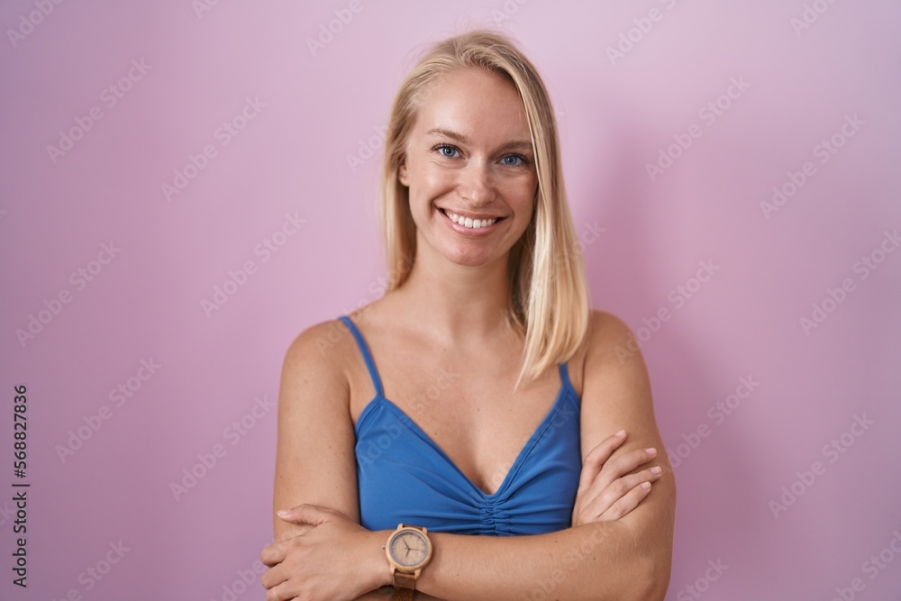 Poster young caucasian woman standing over pink background happy face smiling with crossed arms looking at 