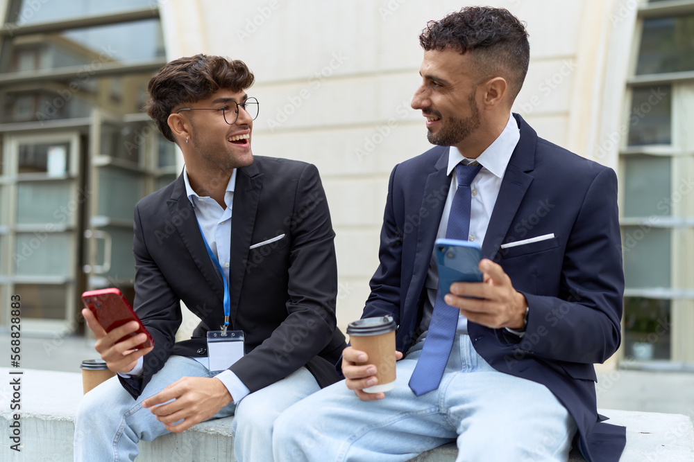 Wall mural Two hispanic men business workers using smartphones drinking coffee at street