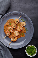 Party snacks. Grilled shrimps on skewers on the plate close up. Seafood barbecue, roast prawns flat lay