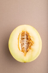 Sliced ripe yellow melon on brown pastel background. Top view, copy space.