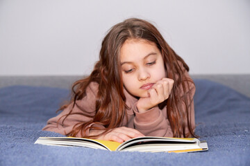 Teen girl reading an interesting book indoor. Youth and literature.