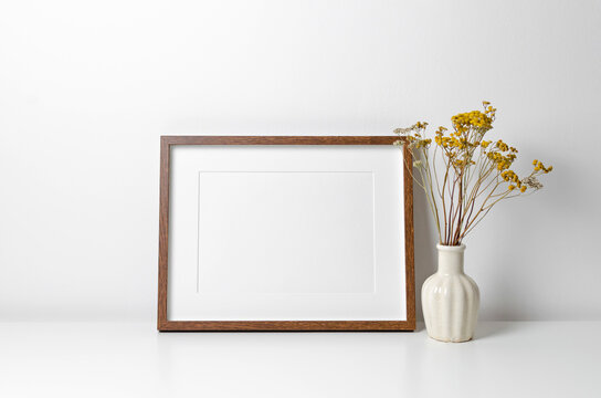 Landscape picture frame mockup in white minimalistic interior with dry flowers decor