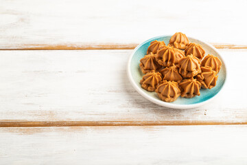 Homemade soft caramel fudge candies on white wooden, side view, copy space.