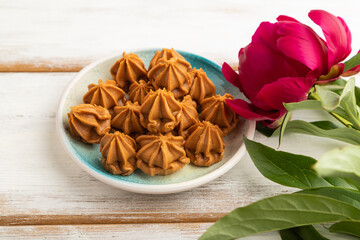 Homemade soft caramel fudge candies on white wooden, side view