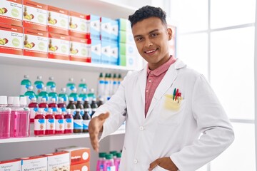 Young latin man pharmacist smiling confident shake hand at pharmacy
