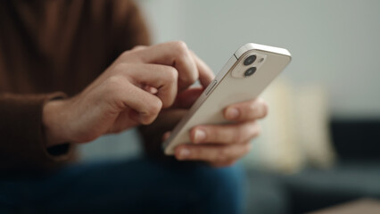 Young hispanic man using smartphone sitting on sofa at home